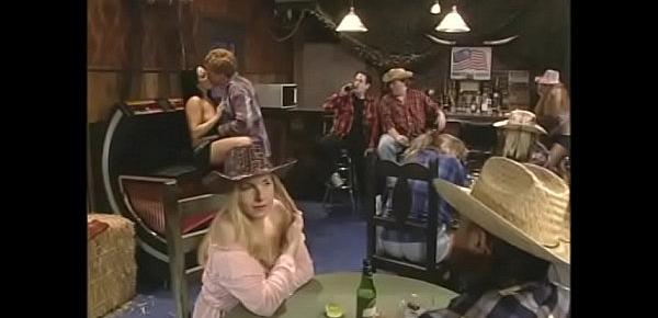  Red-haired guy fucks a slutty brunette in a cowboy hat in front of the visitors of the bar